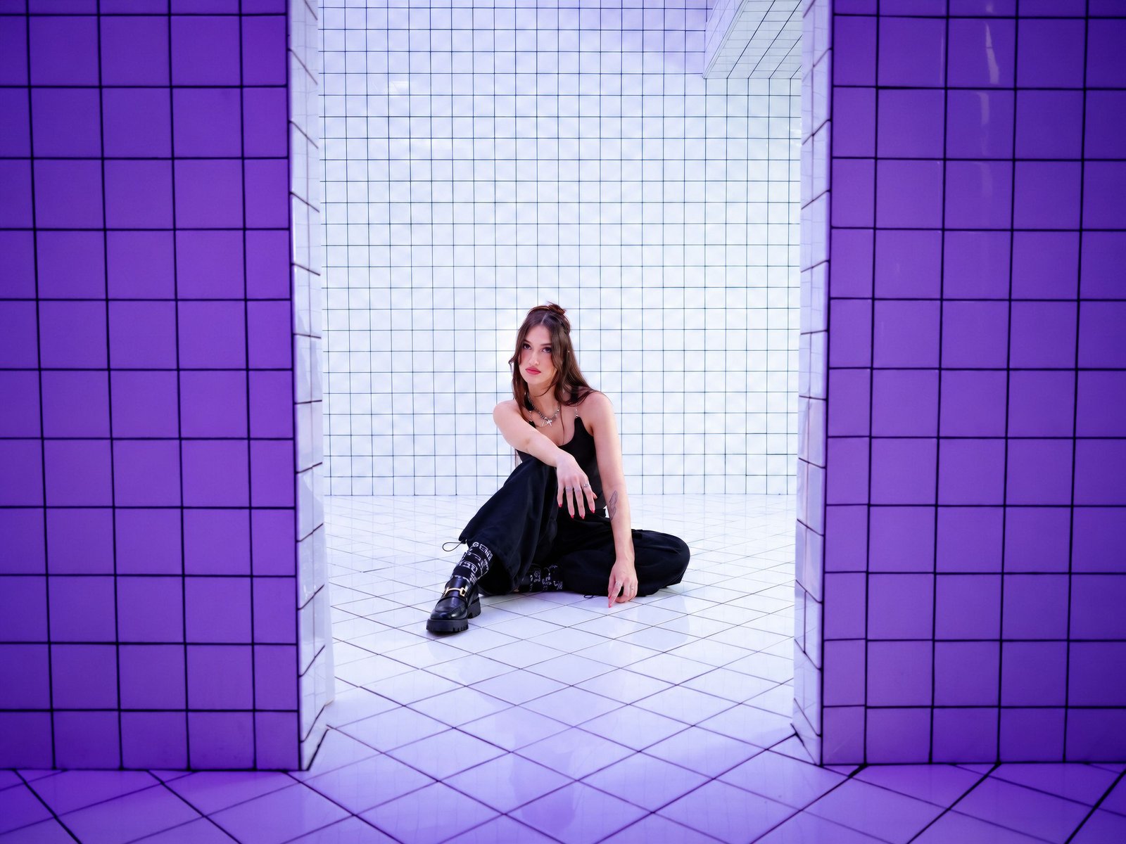 ALLEYCVT seated in a white-tiled room framed by violet tile walls